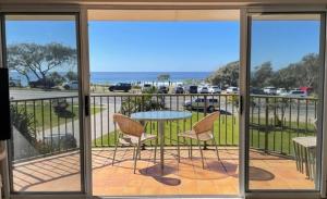 patio con mesa y sillas en el balcón en Cabarita Beachfront Apartments by Kingscliff Accommodation, en Cabarita Beach