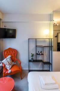 1 dormitorio con 1 cama y 1 silla naranja en Japie rooms - in the heart of Antwerp, en Amberes