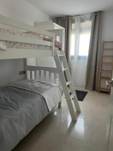 Litera blanca en habitación blanca con escalera en Apartamento Turístico Julia Gemella Acci, en Guadix