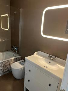 ein Badezimmer mit einem Waschbecken, einem WC und einem Spiegel in der Unterkunft Apartamento Turístico Julia Gemella Acci in Guadix