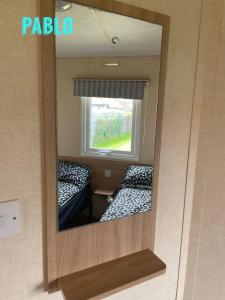 a mirror with a reflection of two beds in a room at Towyn six berth en suite caravan in Rhyl