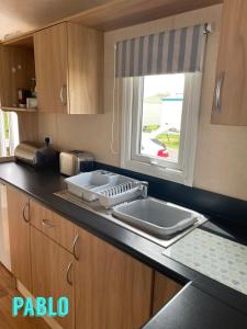 a kitchen with a sink and a window at Towyn six berth en suite caravan in Rhyl