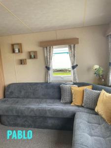 リルにある2 Bedroom 6 berth Caravan Towyn Rhylの窓付きのリビングルーム(青いソファ付)