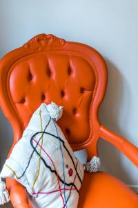 un animal de peluche está sentado en una silla naranja en Japie rooms - in the heart of Antwerp, en Amberes
