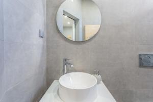 ein Badezimmer mit einem weißen Waschbecken und einem Spiegel in der Unterkunft Wonderful Brand New Apartment Belém - A few steps away from the River! in Lissabon