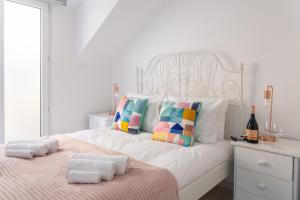 ein weißes Schlafzimmer mit einem Bett mit Handtüchern darauf in der Unterkunft Wonderful Brand New Apartment Belém - A few steps away from the River! in Lissabon