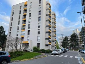 un grand bâtiment blanc avec des voitures garées dans un parking dans l'établissement Bel appartement composé de deux chambres, à Saint Etienne