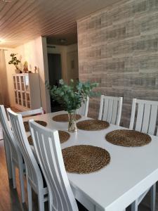 uma mesa branca com cadeiras brancas e um vaso com flores em Omakotitalo hyvällä sijainnilla em Muurame