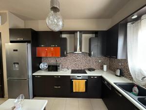a kitchen with black cabinets and a stainless steel refrigerator at Eva’s House in Vari