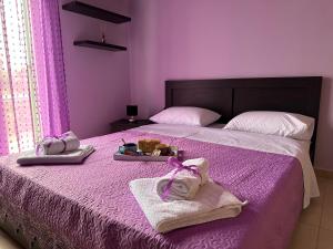 a purple bedroom with a bed with purple sheets and towels at Eva’s House in Vari