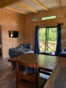 a living room with a wooden table and a television at Cabaña playa Chauquen, Panguipulli in Panguipulli