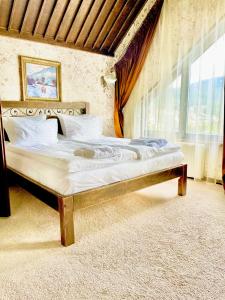ein großes Bett in einem Zimmer mit Fenster in der Unterkunft Nordian chalet next to Bukovel ski lift in Bukowel