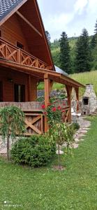 a wooden house with a porch with flowers in front of it at Agroturystyka "Domek pod Praszywką" in Rycerka Górna