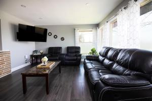 a living room with a leather couch and a table at The Grand Gorge Villa-With Private Yard & Parking, Minutes From Falls & Casino by Niagara Hospitaliy in Niagara Falls