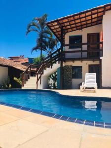 a swimming pool with a chair next to a house at Pousada Sossego do Pirata in Arraial d'Ajuda