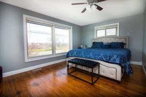 a bedroom with a bed with a blue comforter and two windows at The Grand Gorge Villa-With Private Yard & Parking, Minutes From Falls & Casino by Niagara Hospitaliy in Niagara Falls