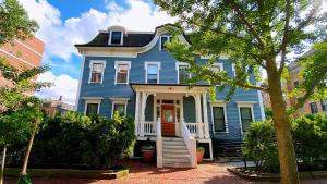 een blauw huis met een witte veranda en een trap bij Ginkgo House on Harvard in Cambridge