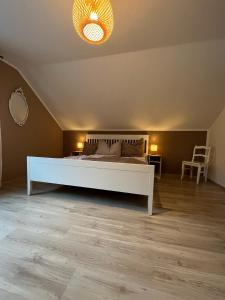 1 dormitorio con 1 cama blanca y 1 silla en Lochhof Zwei - Eifelurlaub mit Farmcharme, en Hellenthal