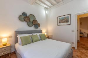 a bedroom with a white bed with two green pillows at Tina’s House in Cortona