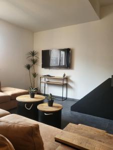 sala de estar con sofá y TV en la pared en Loogiez, en Tongeren