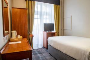 a hotel room with a bed and a desk and a television at Arnos Manor Hotel in Bristol