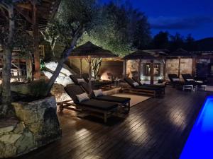 una terraza con sillas y una piscina por la noche en Chambre d'hôte Casa Maredda, en Porticcio