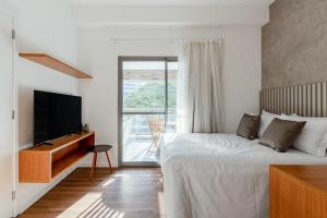 um quarto branco com uma cama e uma televisão em Tabas - Edifício Z. Pinheiros em São Paulo