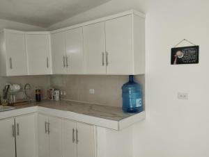 una cocina con armarios blancos y una botella de agua azul en Depto. con Jacuzzi aeropuerto, en Chihuahua