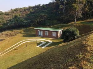 a small house on top of a hill with a driveway at Hoopoe Cottage in Drummond