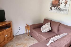 a living room with a couch and a television at Hoopoe Cottage in Drummond