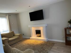 a living room with a fireplace with a tv on the wall at The Nest in Belfast