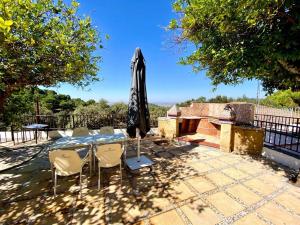 un patio con una mesa con sillas y una sombrilla en Casa 3 habitaciones y Piscina de temporada compartida - - Jacuzzi Spa No incluido -- By TrassierraRooms, en Córdoba
