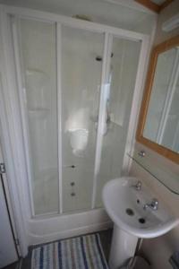 a white bathroom with a shower and a sink at Bay View - fantastic views of Whitsand Bay in Torpoint