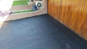 a porch with a black floor next to a wooden fence at Casa Grande pileta próximo kempes y aeropuerto Córdoba Capital in Córdoba