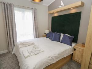 ein Schlafzimmer mit einem großen Bett mit blauen Kissen in der Unterkunft 48 Crosswinds in Bembridge