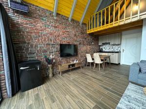 a living room with a brick wall and a television at ROSE SAPANCA STONE HOUSE in Sakarya