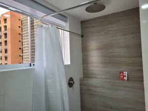 a shower with a white shower curtain next to a wooden door at Apartaestudio 21 Detrás del Hyper Jumbo con planta eléctrica in Maracay