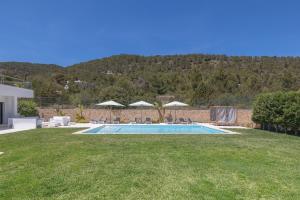 una piscina en un patio con sillas y sombrillas en Villa con vistas al mar, en Sant Jordi