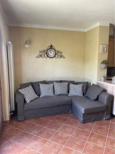 un divano in soggiorno con un orologio sul muro di CS Holiday a Castelnuovo Berardenga