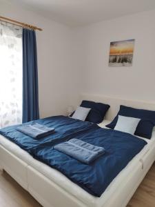 Una cama con sábanas azules y toallas. en Holling apartman, en Fertőboz