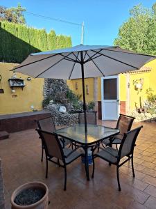 una mesa y sillas con una sombrilla en el patio en VILLA EL SALADO -ALQUILER RURAL ISABEL en Arriate