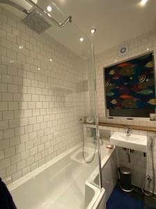 a bathroom with a shower and a tub and a sink at Three Bedroom Family home with garden in Walthamstow in London
