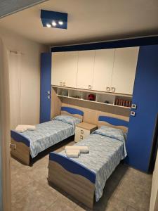 2 łóżka w pokoju z niebieskimi ścianami i białymi szafkami w obiekcie Cammy's house w mieście Monreale
