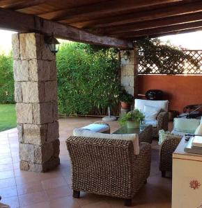 a patio with wicker tables and chairs and a stone pillar at Villa quadrilocale vista mare veranda e giardino in Cannigione