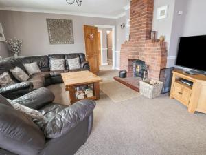 a living room with a leather couch and a fireplace at Beach Cottage in Rhyl