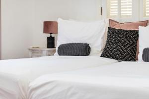 Una cama blanca con almohadas y una lámpara en una mesa. en Villa Aventura, en Kralendijk