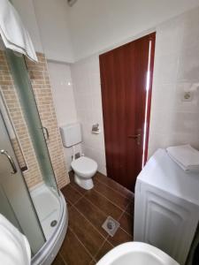 a bathroom with a toilet and a wooden door at Apartmani Apollo - Drasnice in Drasnice