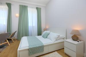 een slaapkamer met een bed met groene gordijnen en een bureau bij Bed & Breakfast- La Villa Lopud in Lopud Island