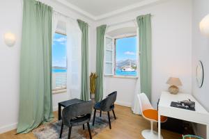 a living room with a desk and chairs and windows at Bed & Breakfast- La Villa Lopud in Lopud Island