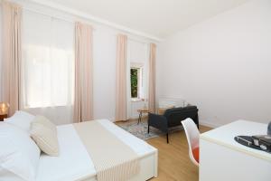 een witte slaapkamer met een wit bed en een stoel bij Bed & Breakfast- La Villa Lopud in Lopud Island